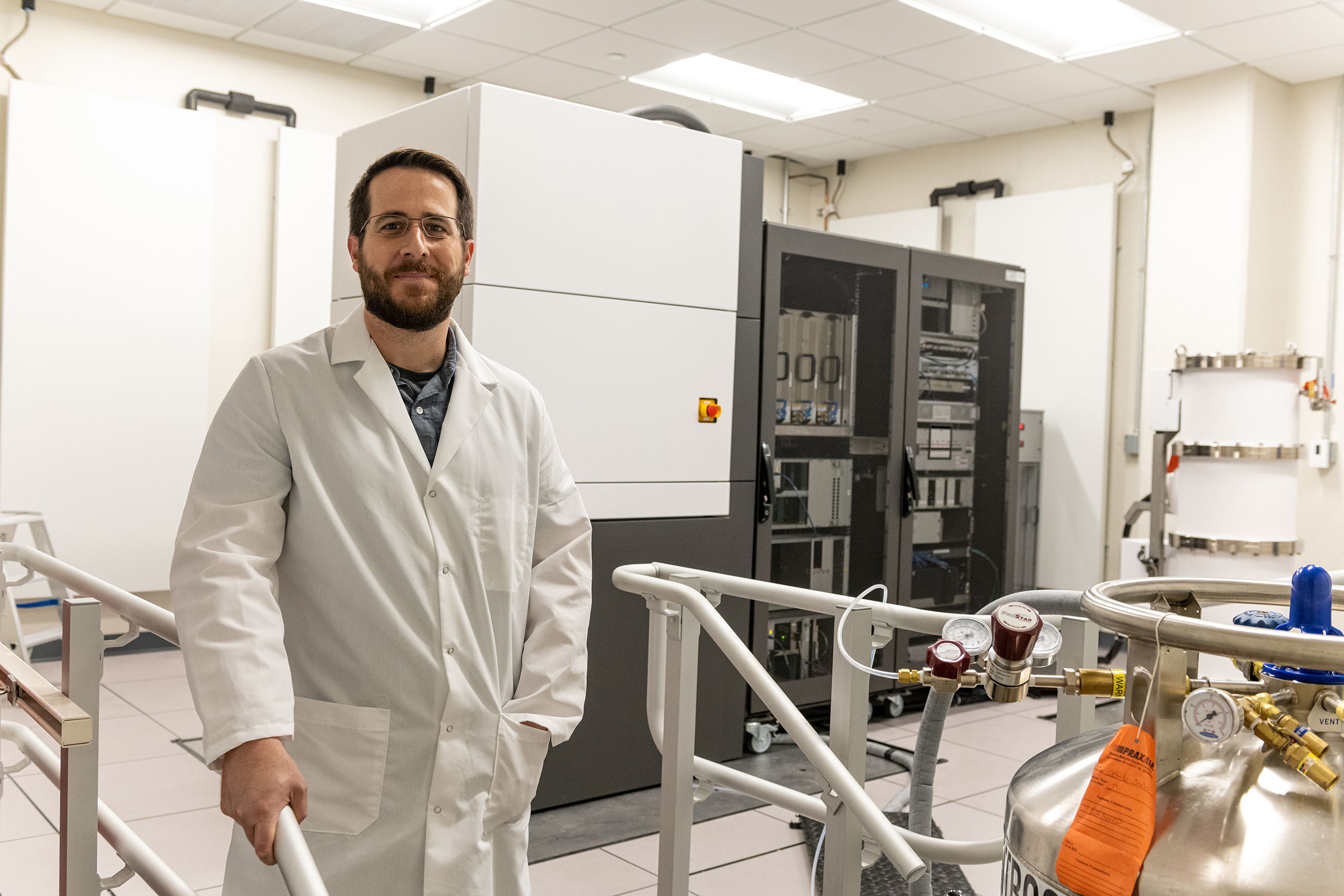 Man in a white lab coat standing in front of scientific equipment